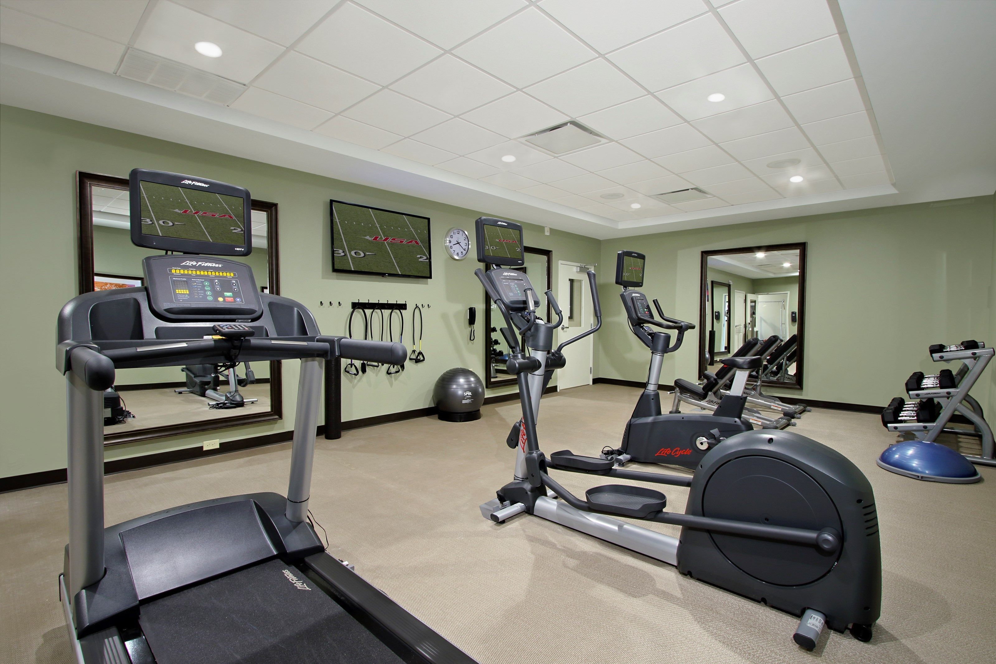 Une salle de sport équipée de tapis de course, de vélos elliptiques et de matériel de musculation.