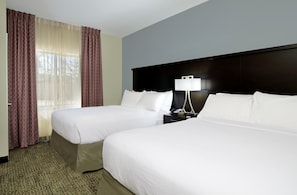 A hotel room with two beds, a dark headboard, a bedside table with a lamp, and a large window with curtains. - Accessible 2BR Suite | Free Daily Breakfast + Pool (Houston)