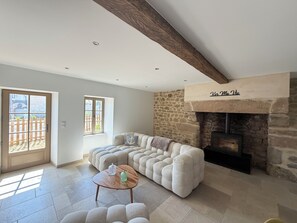 A living room with a stone fireplace, a large sofa, and a wooden coffee table. - Stone house with a hot tub - 4 bedrooms - 800 m from the beach - Batz-sur-Mer (Batz-sur-Mer)