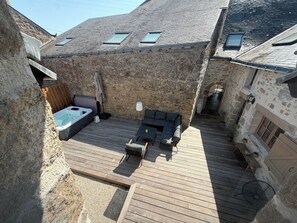 A stone building with a wooden deck, a hot tub, and outdoor seating. - Stone house with a hot tub - 4 bedrooms - 800 m from the beach - Batz-sur-Mer (Batz-sur-Mer)