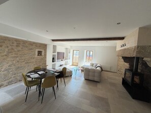 A spacious living area with a stone wall, a fireplace, a dining table with chairs, and a sofa. - Stone house with a hot tub - 4 bedrooms - 800 m from the beach - Batz-sur-Mer (Batz-sur-Mer)