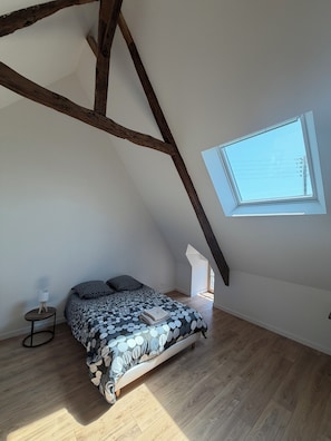 A bedroom with a sloped ceiling, a skylight, a bed with a patterned bedspread, a bedside table with a lamp, and wooden flooring. - Stone house with a hot tub - 4 bedrooms - 800 m from the beach - Batz-sur-Mer (Batz-sur-Mer)