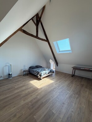 A bedroom with a sloped ceiling, a bed with patterned bedding, a small bedside table, a lamp, and a window. - Stone house with a hot tub - 4 bedrooms - 800 m from the beach - Batz-sur-Mer (Batz-sur-Mer)