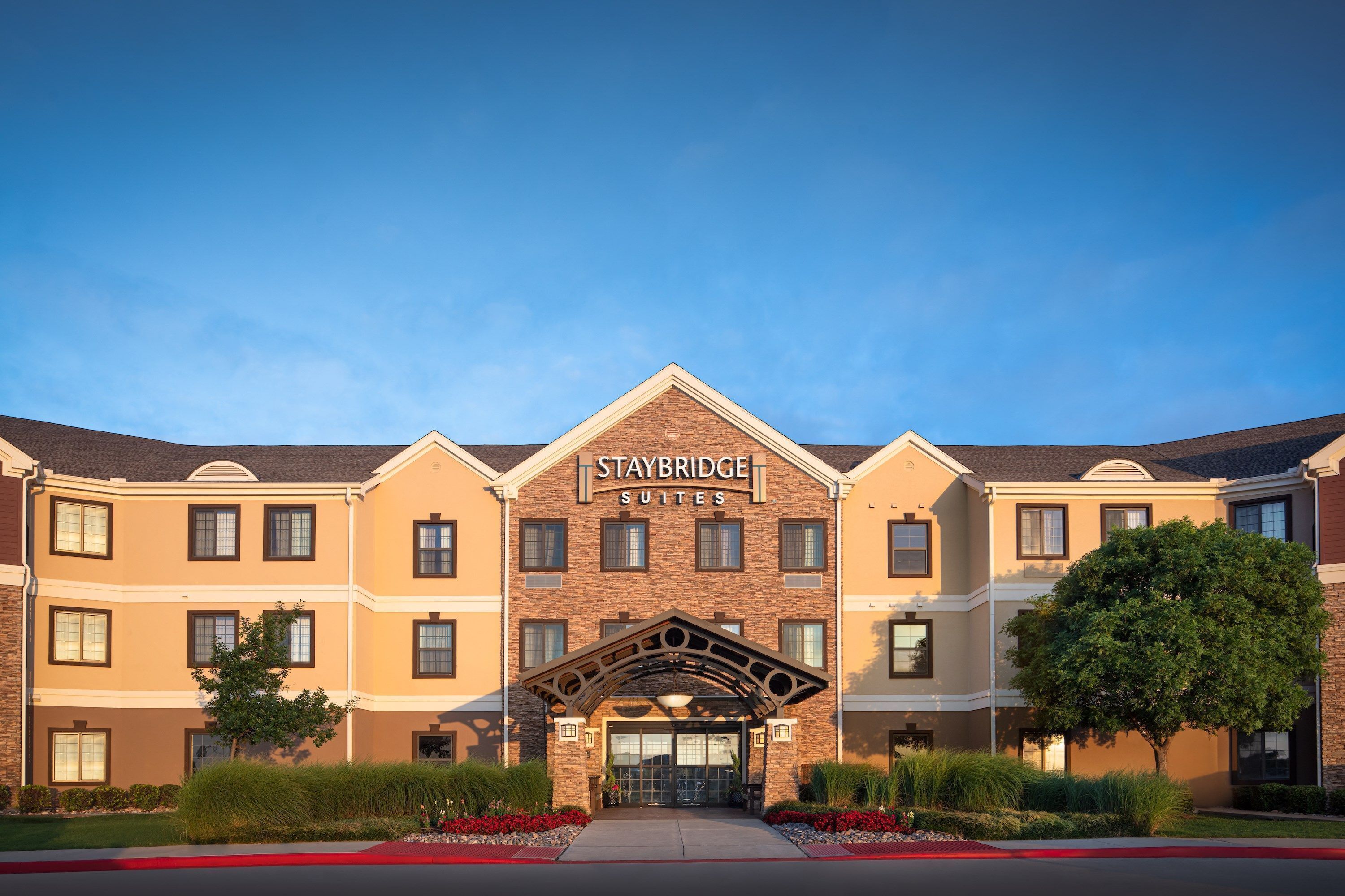 Een Staybridge Suites hotel met een symmetrische gevel, veel ramen en een centrale ingang met een decoratieve boog.