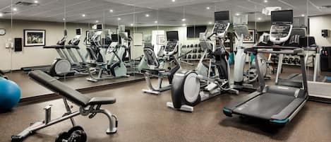 A gym with various exercise equipment, including treadmills, elliptical machines, and weight benches.