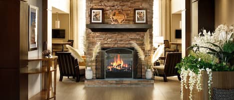A spacious living room with a stone fireplace, framed artwork, and comfortable seating.