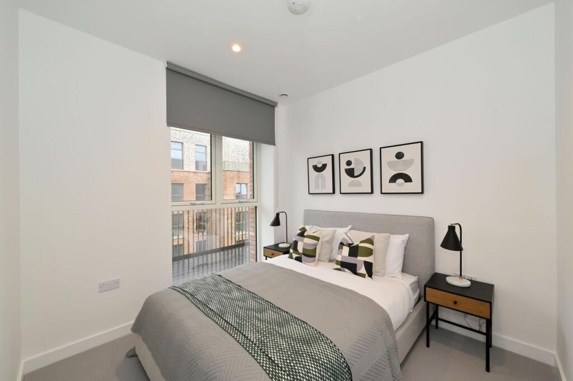 A bedroom with a bed, bedside tables, a window, and artwork on the wall.