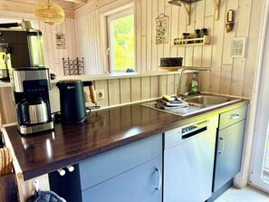 A kitchen with a coffee maker, a sink, and a window. - Charming wooden house by the lake with sauna and boat (Dümmer)