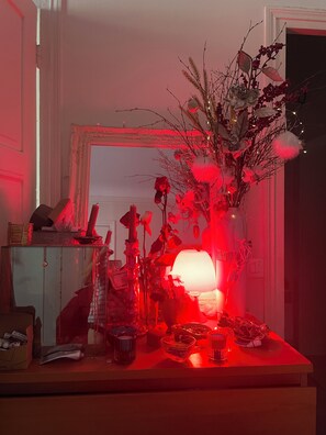 Une pièce avec une table mise pour le repas, un vase contenant des fleurs séchées et un miroir accroché au mur.