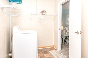A laundry area with a washing machine, drying racks, and a small shelf with a decorative item. - The Treasure Chest 2 - 2BR Ground Floor Unit!  Dog Friendly! Close Beach Access! (Surf City)
