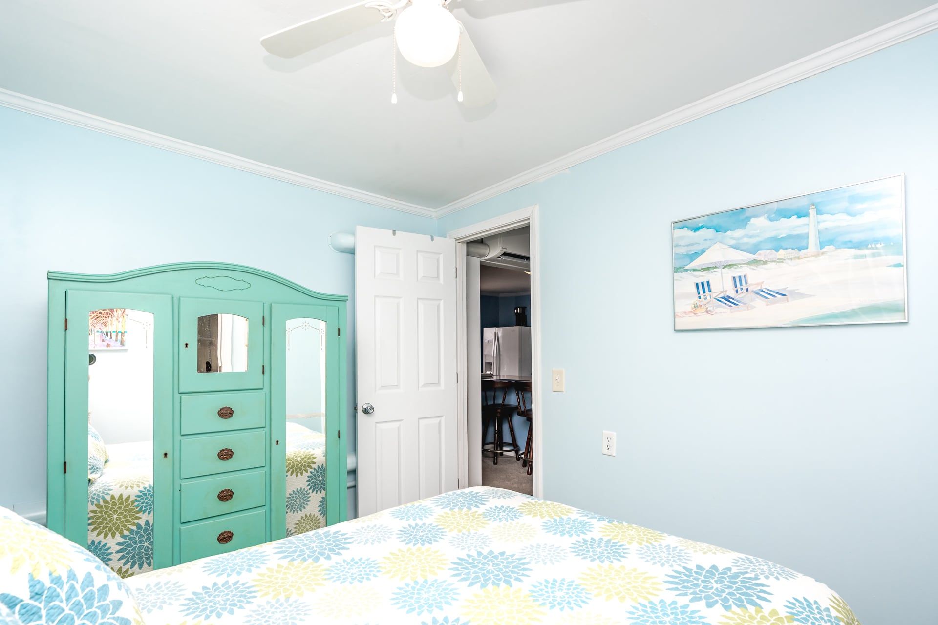 Une chambre à coucher avec un lit, une armoire, une porte donnant sur un couloir et un tableau accroché au mur.