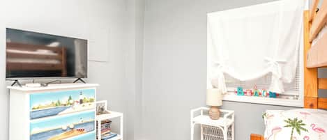 Een kinderkamer met een televisie, een boekenkast en een raam met uitzicht.