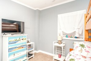Een kinderkamer met een televisie, een boekenkast en een raam met uitzicht.