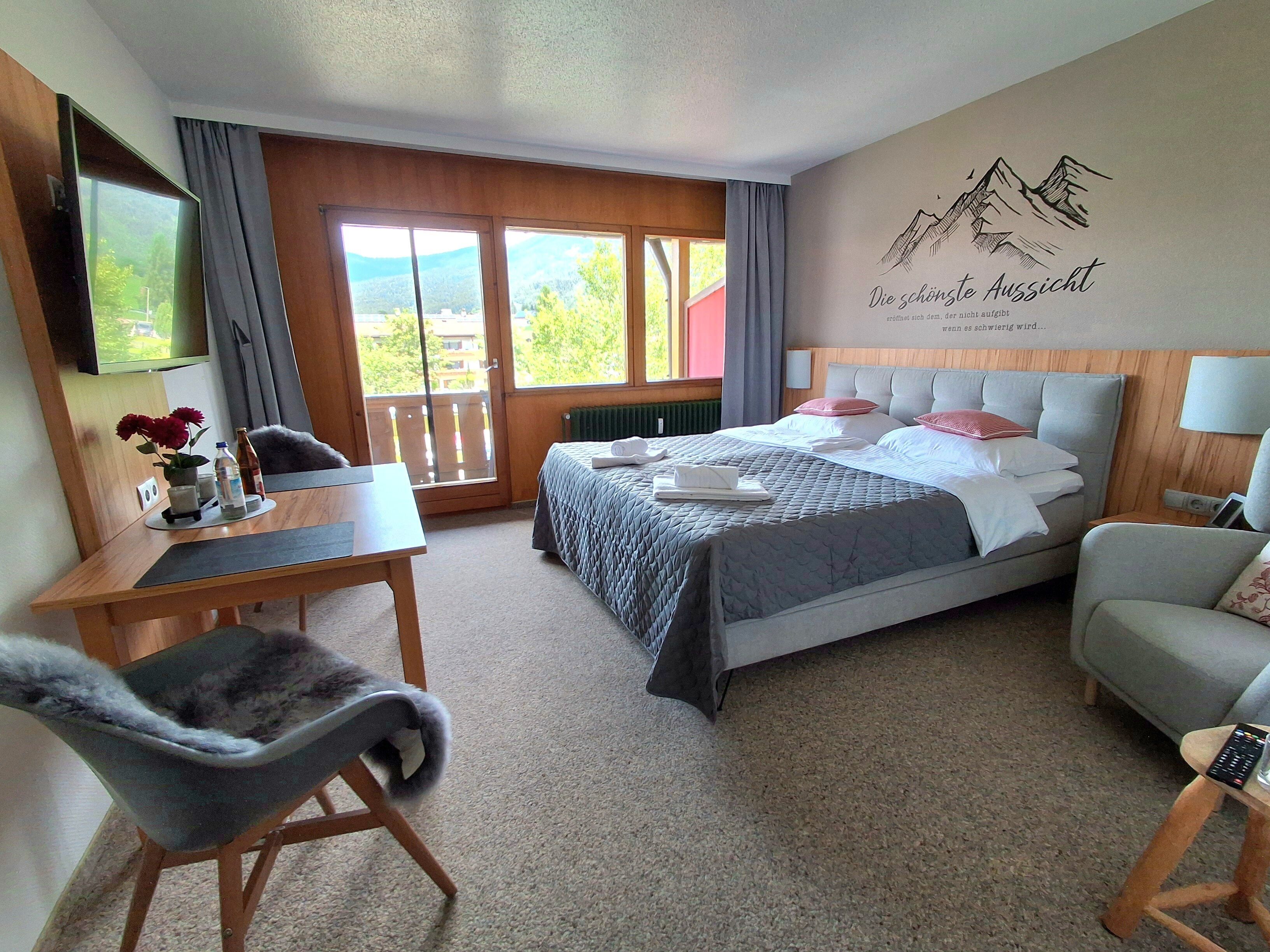 Une chambre d’hôtel équipée d’un lit, d’un bureau, d’une chaise, d’une télévision et offrant une vue sur l’extérieur.