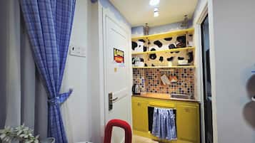 Eine kleine Küche mit einem gelben Schrank, einem roten Stuhl und einem blauen Vorhang.