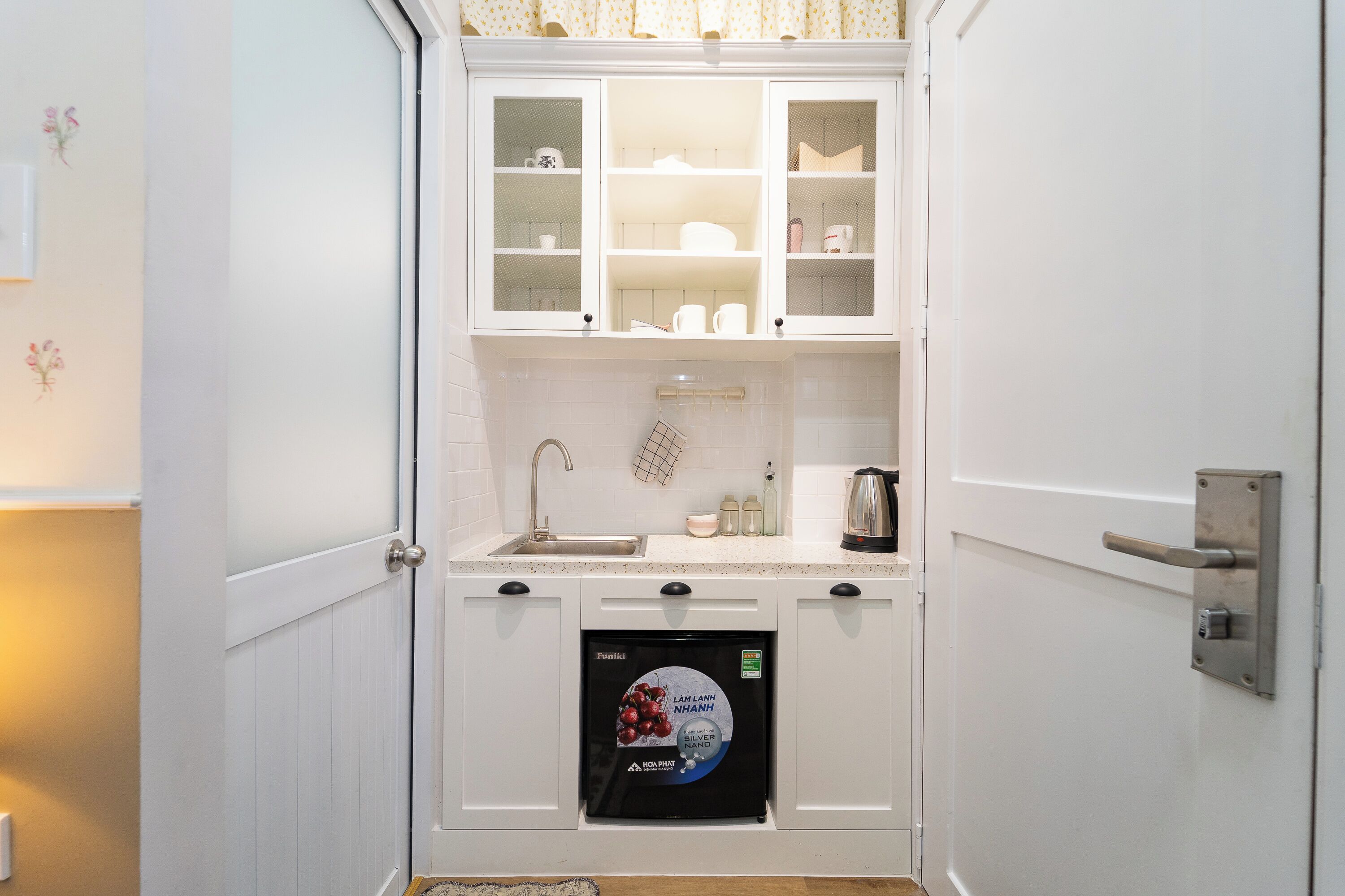 A compact kitchen with a built-in dishwasher, a sink, and a coffee maker.