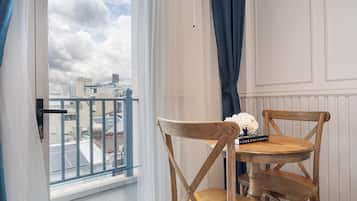 A room with a balcony, a table with chairs, and a view of the cityscape.