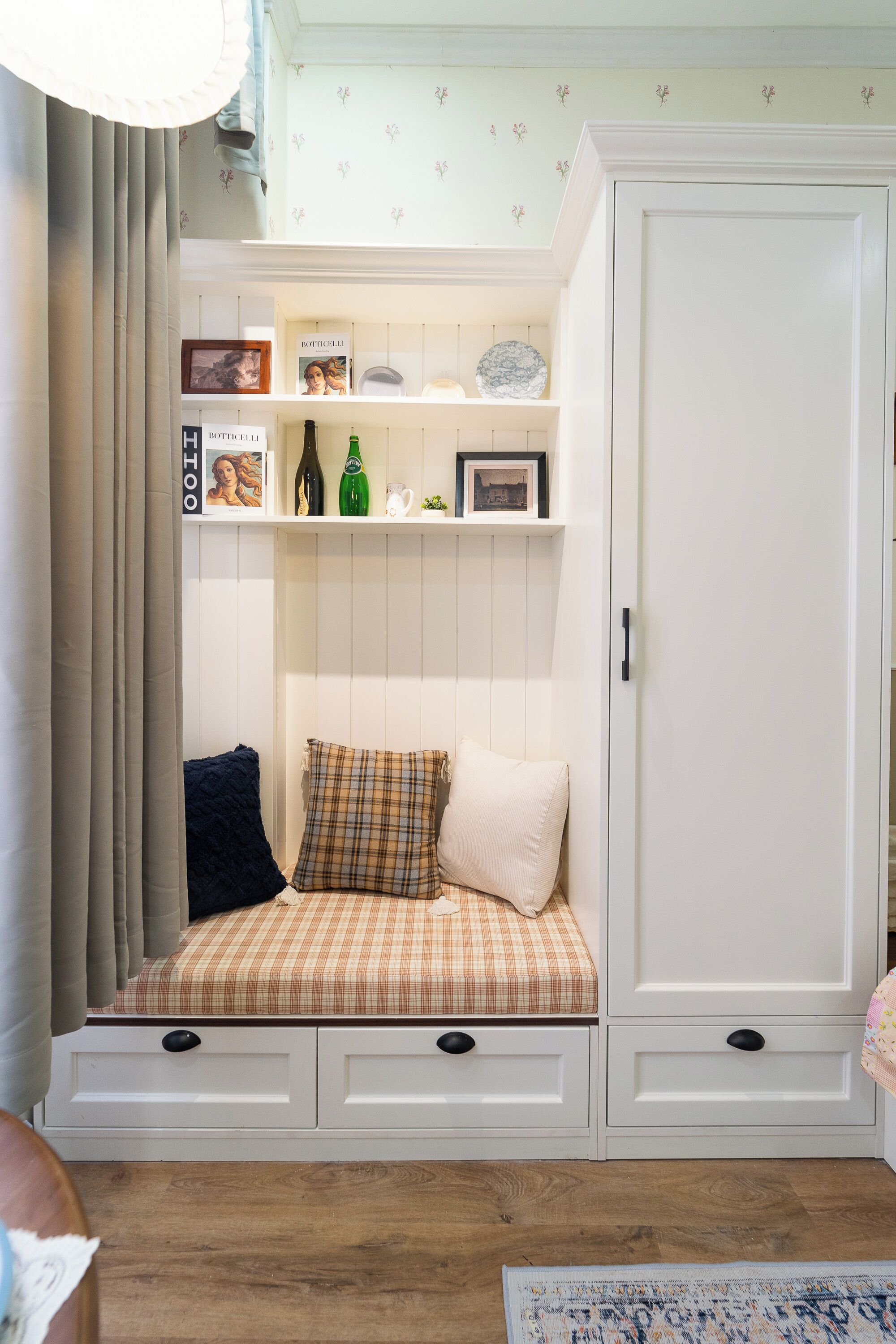 Ein Zimmer mit einer eingebauten Sitzecke, einem Kleiderschrank und einem Regal mit diversen Gegenständen.