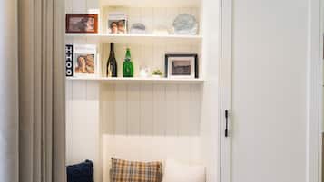 Ein Zimmer mit einer eingebauten Sitzecke, einem Kleiderschrank und einem Regal mit diversen Gegenständen.