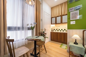 A compact kitchen with wooden cabinets, a dining area with a table and chairs, and a view of the adjacent living space.