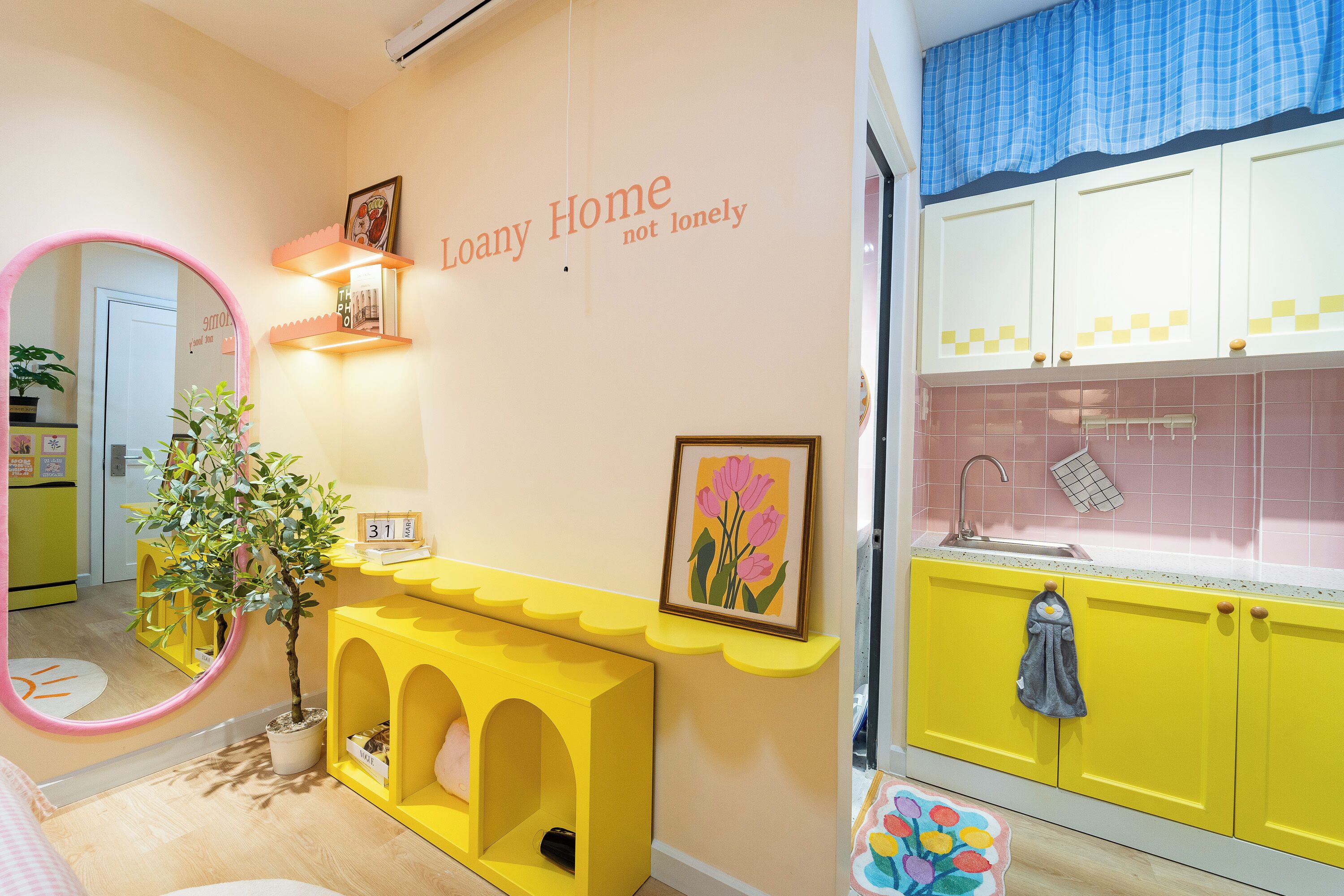 A brightly colored interior with a yellow console table, a mirror, and a wall-mounted shelf with books and a calendar.