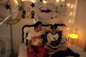 A room with a bed, a calendar, string lights, and wall decorations.