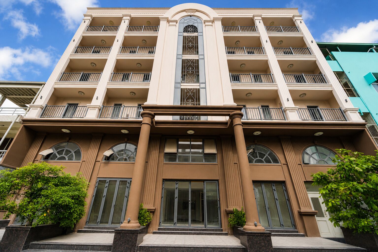 Een meerlaags hotel met een centrale ingang, balkons op elke verdieping en een modern architectuur.