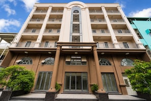 Un hotel de varios pisos con una entrada central, balcones en cada nivel y un diseño arquitectónico moderno.