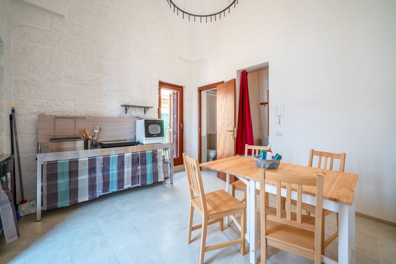 A compact kitchen with a microwave, a small stove, and a checkered tablecloth.