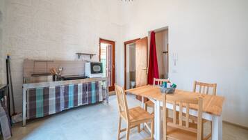 A compact kitchen with a microwave, a small stove, and a checkered tablecloth.