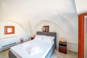 Ein Schlafzimmer mit einem Bett, einem Nachttisch, einer Wandradiatore und einem Feuerlöscher.