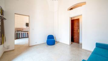 A spacious living area with a blue sofa, a blue chair, and a wooden door.
