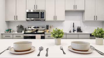 A modern kitchen with white cabinets, stainless steel appliances, and a central island with two bowls and cutlery.
