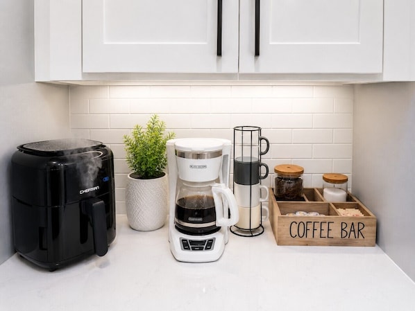 Una cocina con cafetera, máquina de café, barra de café y una planta.