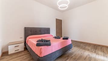 A bedroom with a bed, a nightstand, a door, and a modern light fixture.