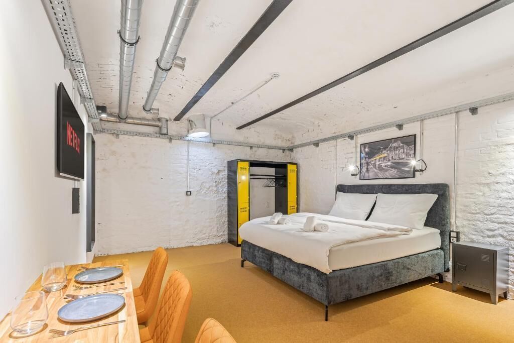 Une chambre à coucher avec un lit, un bureau avec des chaises et un téléviseur.