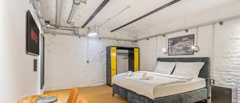 Une chambre à coucher avec un lit, un bureau avec des chaises et un téléviseur.