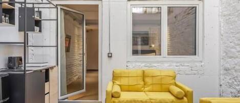 A loft-style apartment with a high ceiling, a balcony, and a kitchen area.