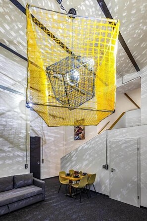 A room with a geometric hanging light fixture, a dining table with chairs, and a sofa.