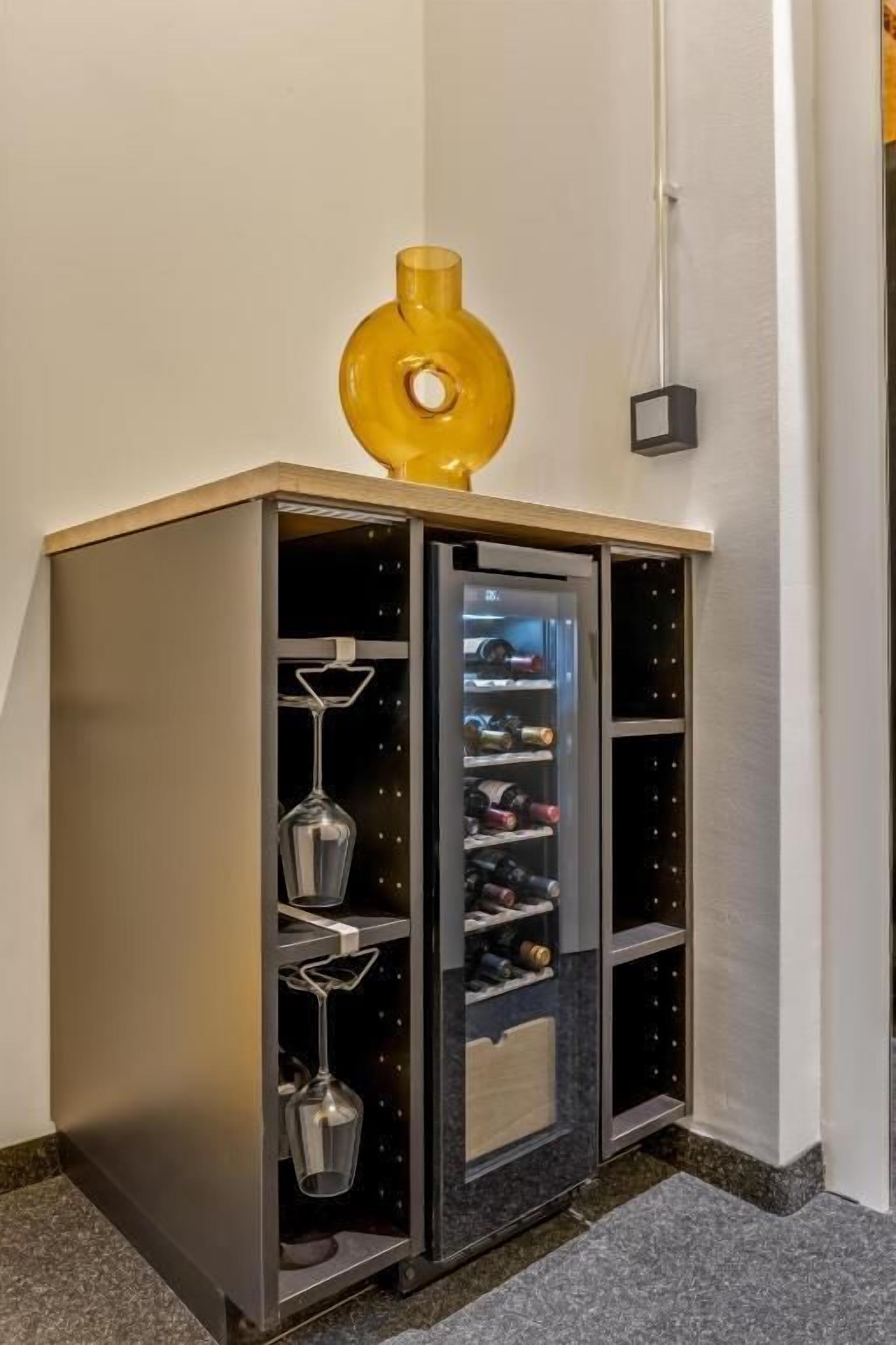 Un mueble esquinero con varios compartimentos, que incluye un botellero y estantes para botellas.