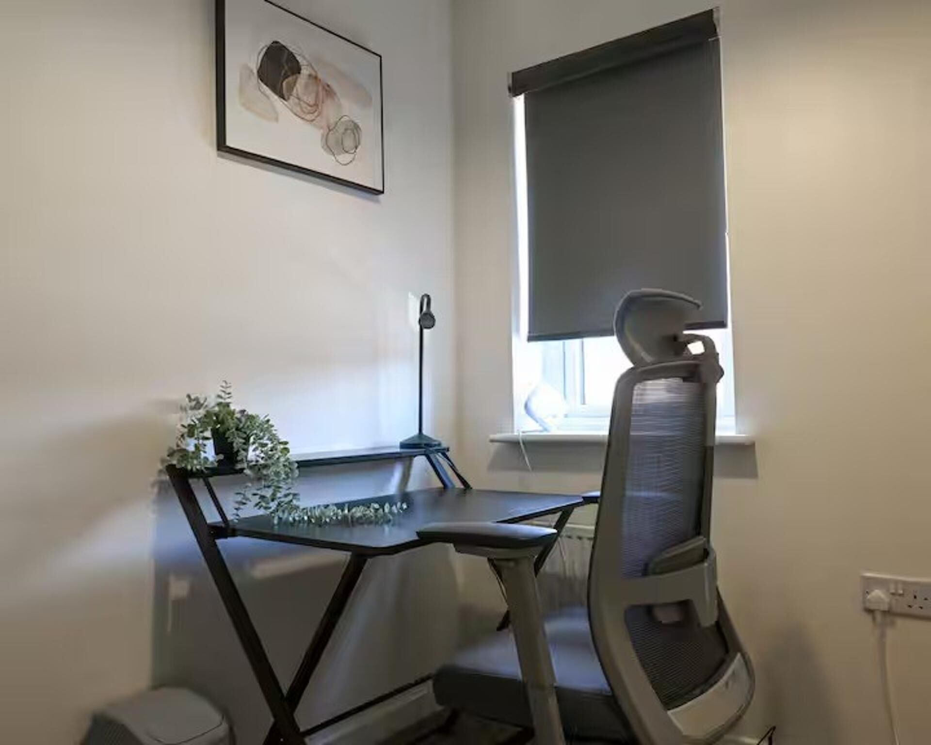 A workspace with a desk, chair, and a window with a blind.
