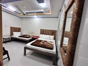 Habitación de hotel con dos camas, un ventilador de techo y un espejo grande.