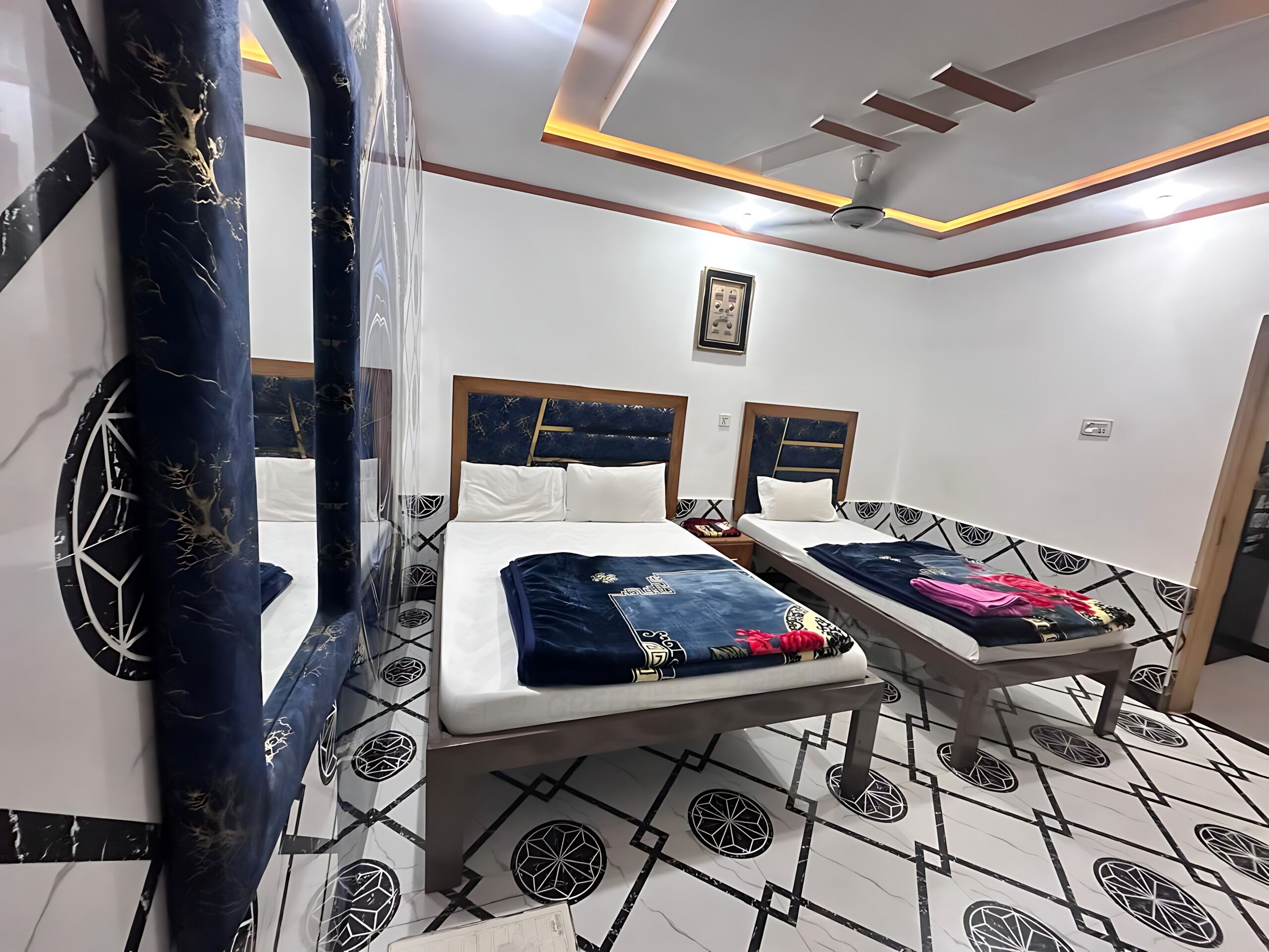 Quarto de hotel com duas camas, um ventilador de teto e piso estampado.