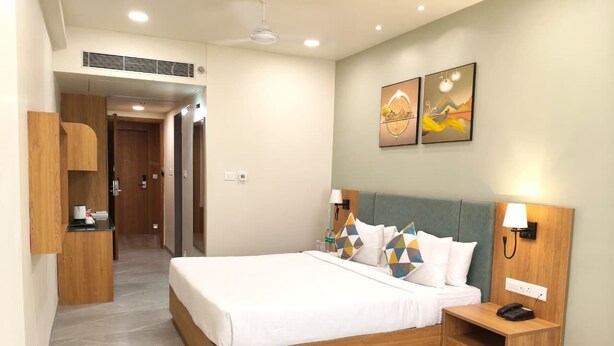 Una habitación de hotel con cama, mesitas de noche, escritorio y obras de arte en la pared.
