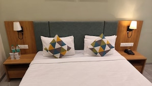 Una habitación de hotel con una cama, dos mesitas de noche, una lámpara en cada mesita y una almohada con estampado geométrico.