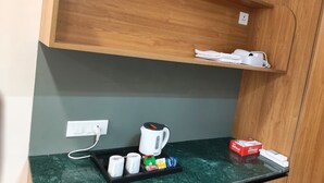 Una kitchenette equipada con cafetera, bolsitas de té, hervidor y una caja de té.
