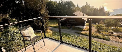 Un balcón con vistas a un paisaje rural, una silla y una mesita.