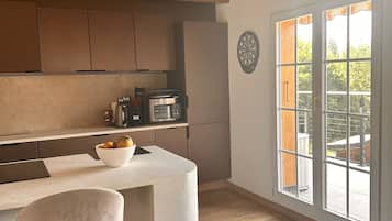 Une cuisine avec un plafond en bois, une grande fenêtre et un coin bar agrémenté d’un saladier de fruits.