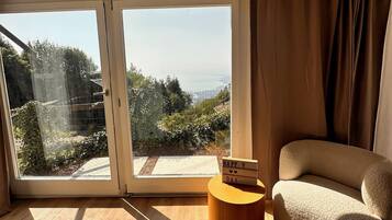 Ein Zimmer mit einer großen Glasschiebetür, einem runden Holznachttisch und einem beigen Sofa.
