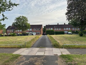 Une rue résidentielle bordée de maisons des deux côtés, avec un trottoir et une zone herbeuse.